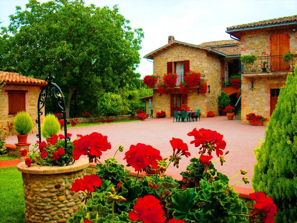 una casa in pietra con fiori rossi in un cortile di Aurora a Gubbio