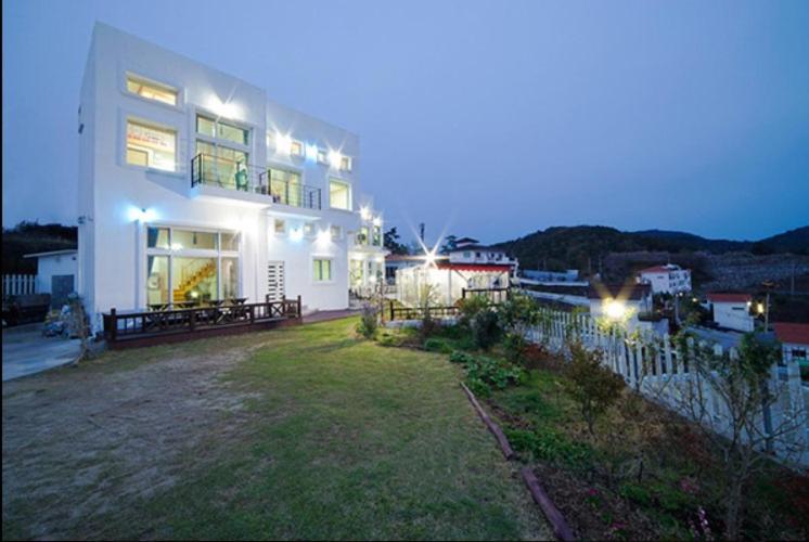 uma grande casa branca com um quintal à noite em Sunmoon Pension em Yeosu