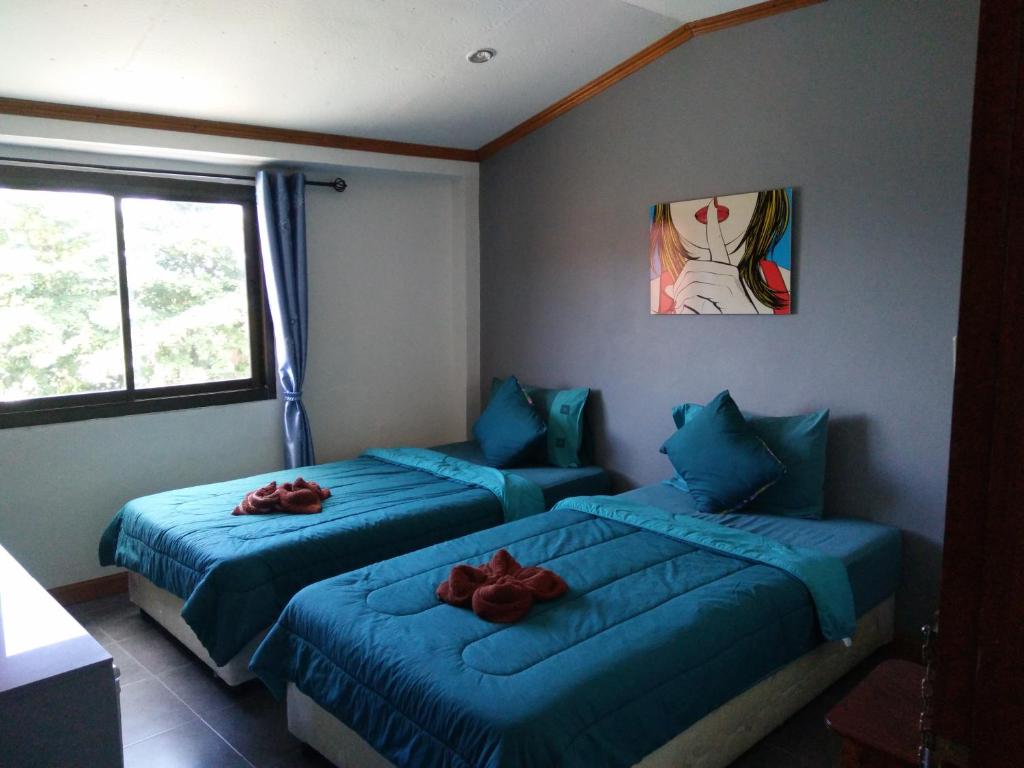 2 lits dans une chambre avec des draps bleus et des roses rouges dans l'établissement Kohkaew Village 2@Kohsamet, à Ko Samet