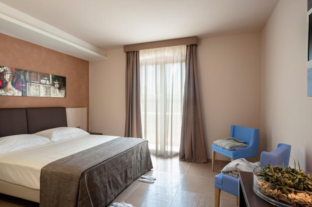 una camera con un letto e due sedie blu di Le Dune Suite Hotel a Porto Cesareo