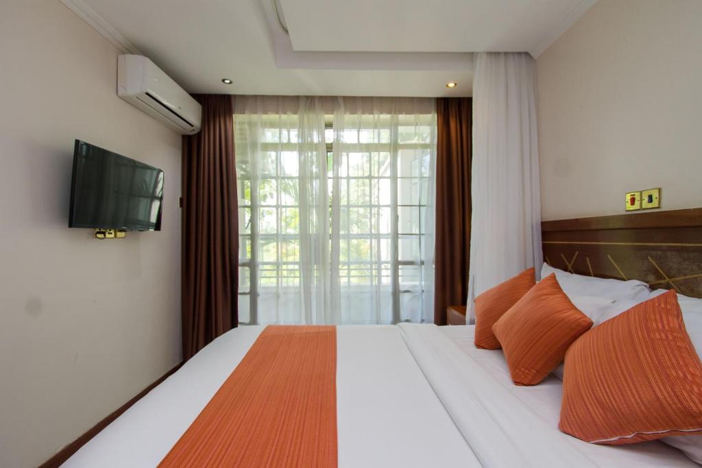 a bedroom with a bed with a tv and a window at Victoria Comfort Inn in Kisumu