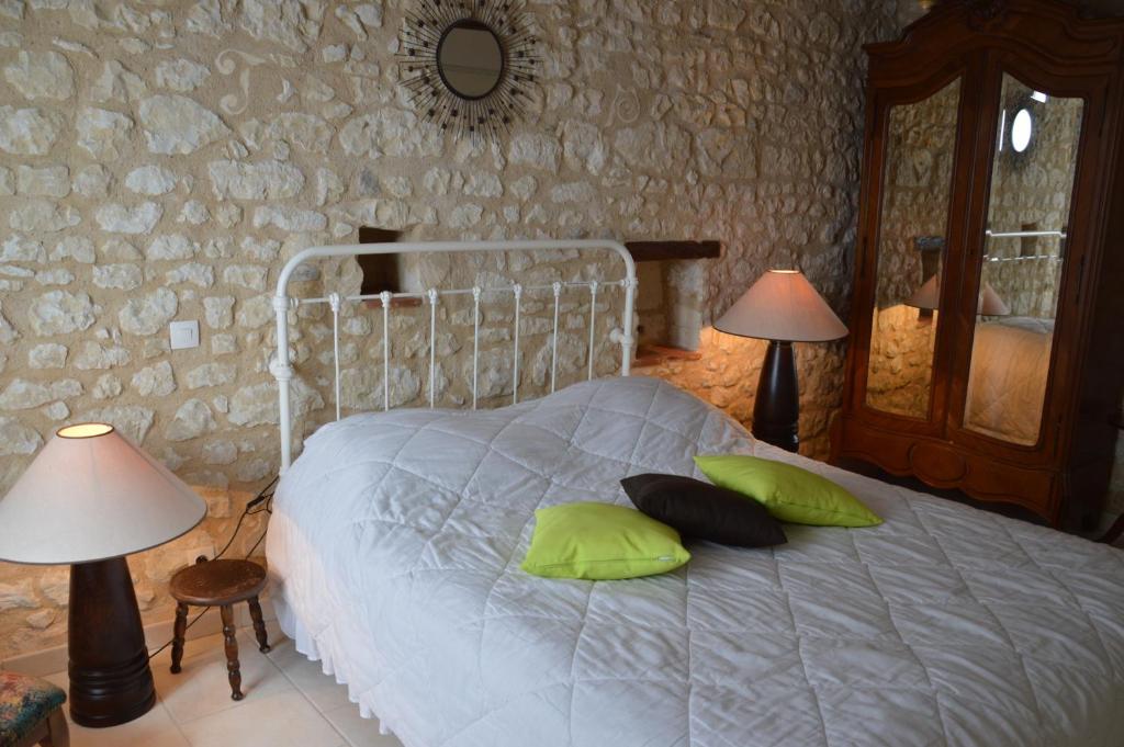 a bedroom with a bed with green pillows and a mirror at Aux Jardin&#39;s de la Bosniere in Cussay