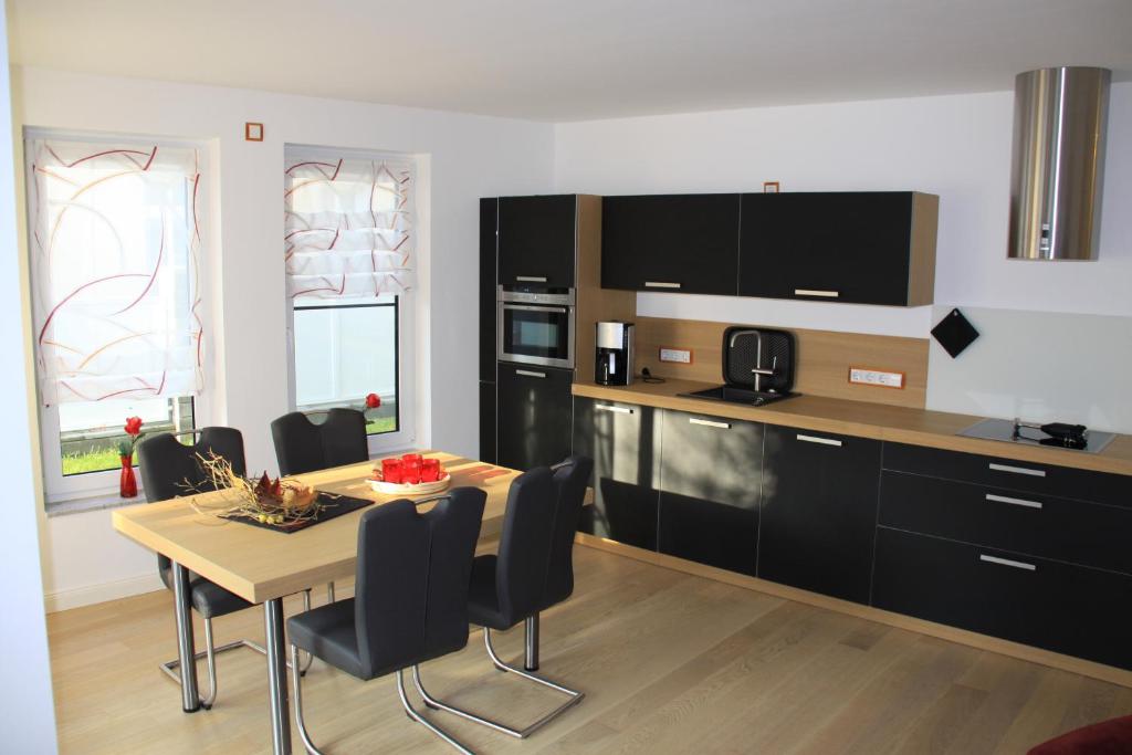 eine Küche mit einem Tisch und schwarzen Schränken in der Unterkunft Villa Gutenberg in Binz