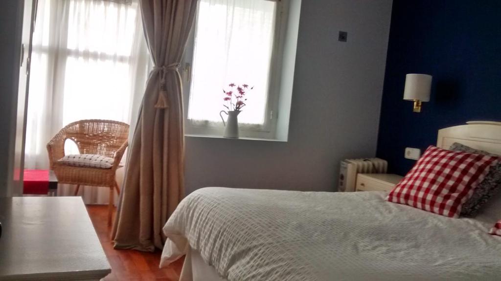 1 dormitorio con cama, ventana y silla en Casa de marinos UribeKosta, en Plentzia