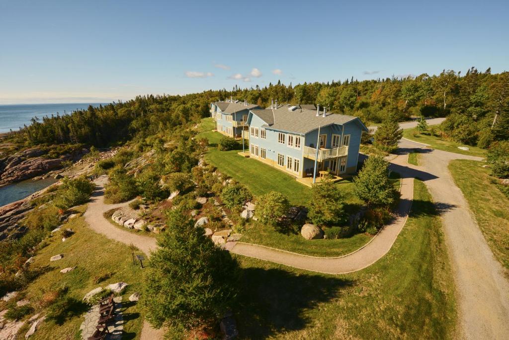 an aerial view of a large house on a hill next to the ocean at Condos-Hotels Natakam, Communauté Autochtone in Les Escoumins