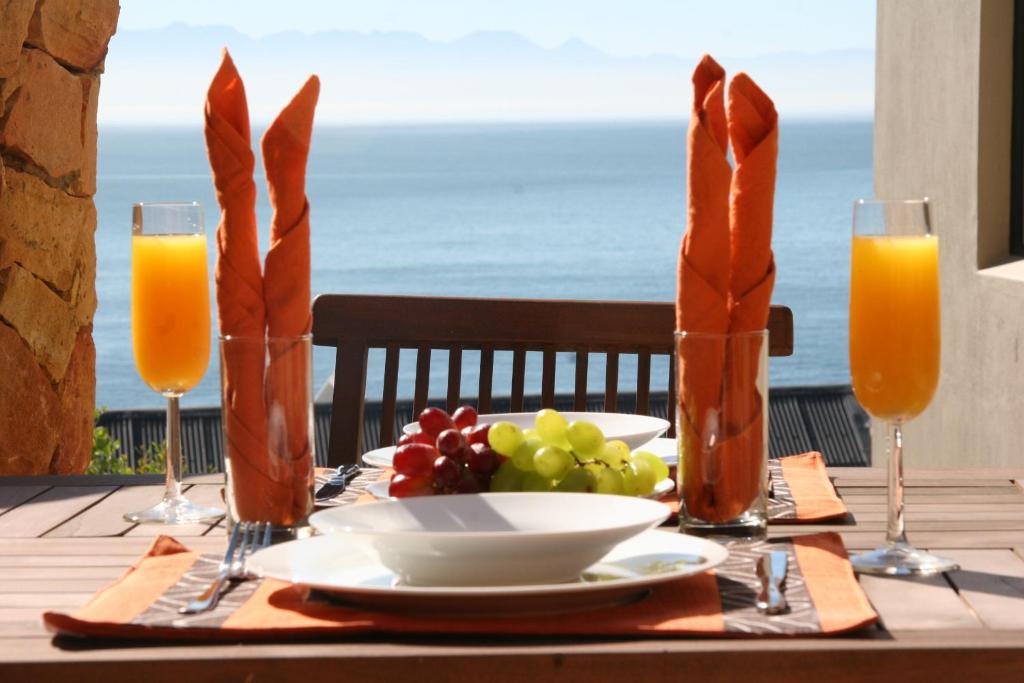 una mesa con un plato de comida y vasos de zumo de naranja en Simon’s Town Guest House, en Simonʼs Town