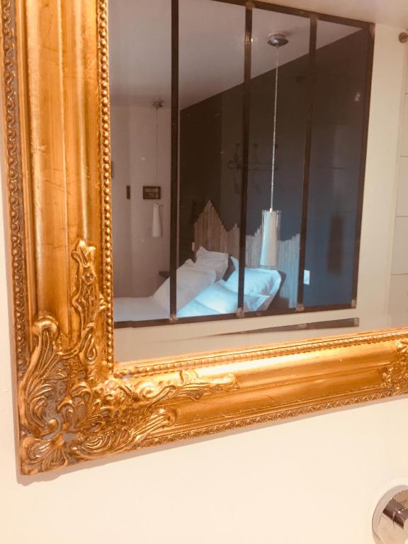 espejo enmarcado en oro en una pared con cama en La Sapinière de Vittel, en Vittel
