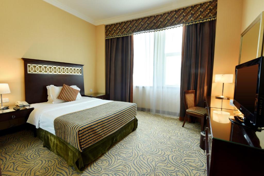 a hotel room with a bed and a television at Concorde Hotel Fujairah in Fujairah