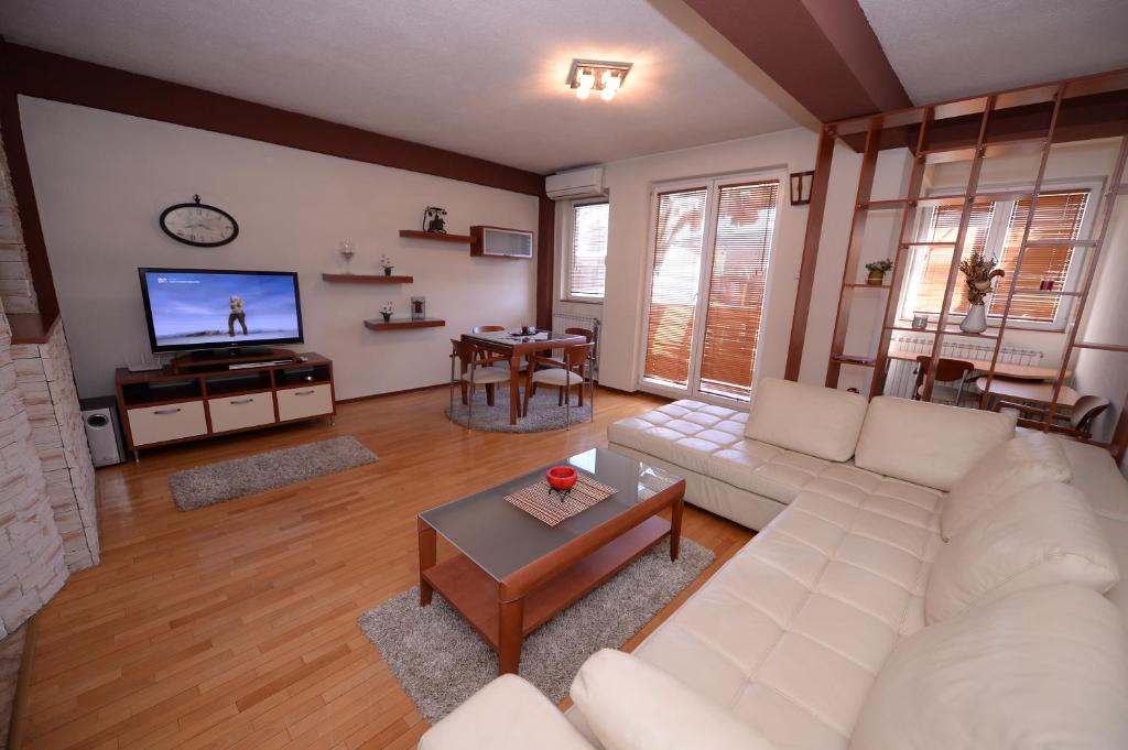 sala de estar con sofá blanco y TV en Exclusive Skopje Apartments, en Skopje