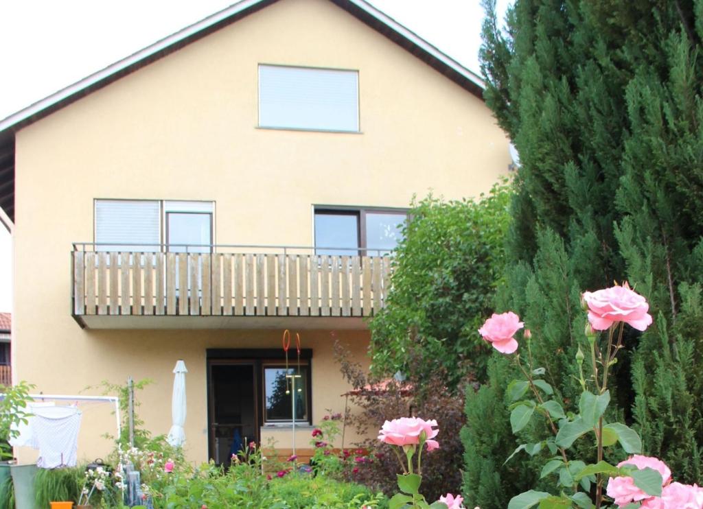 a house with a balcony and pink roses at Vronis Ferienwohnungen in Mühlingen