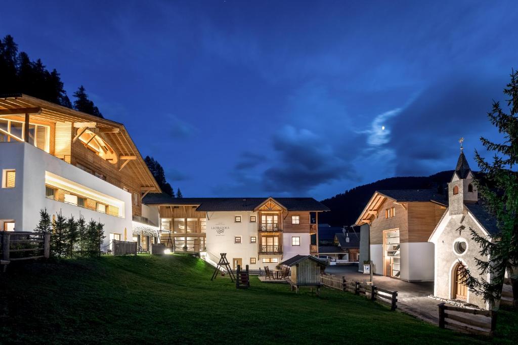 una gran casa con una iglesia y un patio en Hotel La Fradora - Dolomites Hotel en San Cassiano