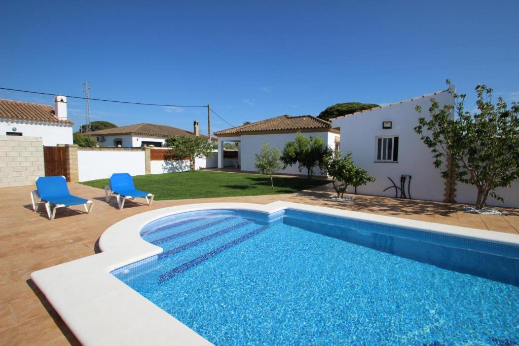 una piscina con 2 sillas azules y una casa en casa Garcia, en Conil de la Frontera