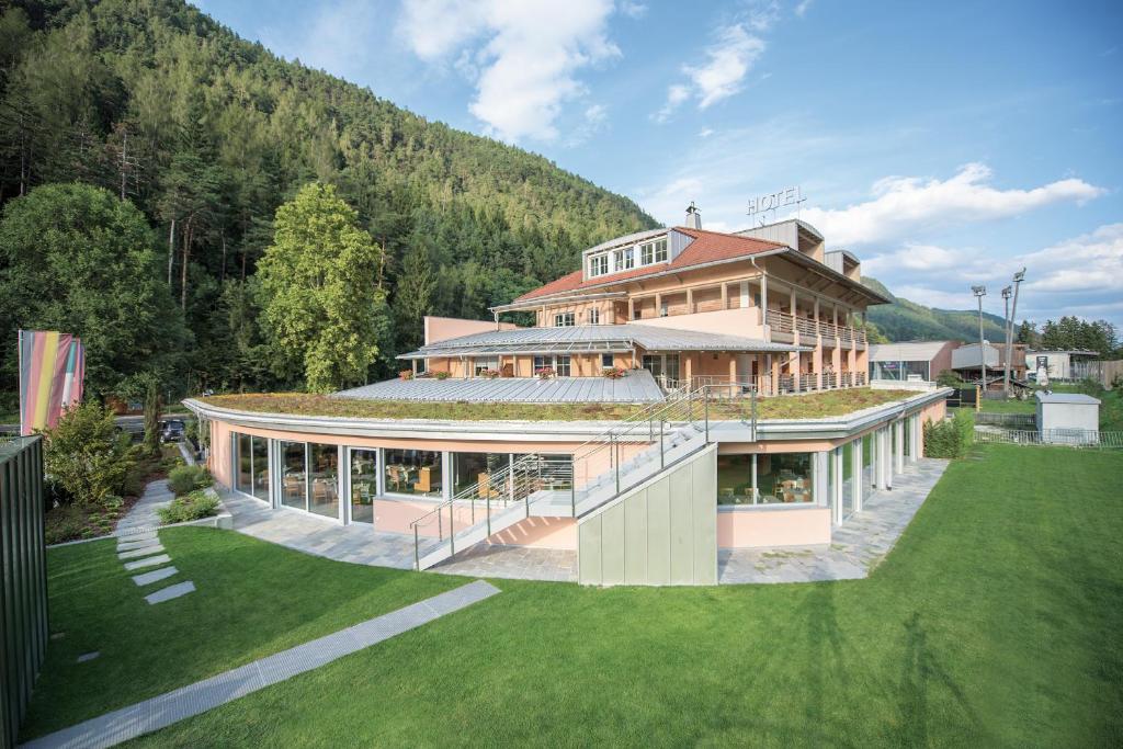 ein großes Haus mit einem Hügel im Hintergrund in der Unterkunft Aktiv & Genusshotel Lodenwirt in Vintl