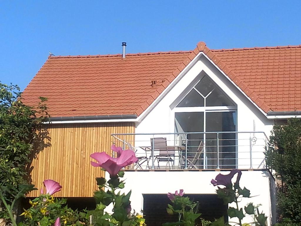 une maison blanche avec un toit rouge et un balcon dans l'établissement La Grange, à Foncquevillers