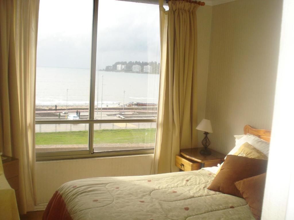 a bedroom with a large window with a view of an airport at Departamento Torres del Mar de Dichato in Dichato