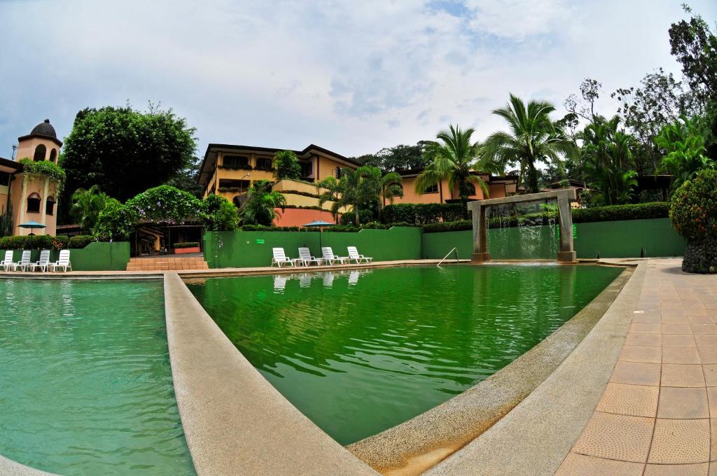 a swimming pool with green water in front of a house at El Tucano Resort & Thermal Spa in Quesada