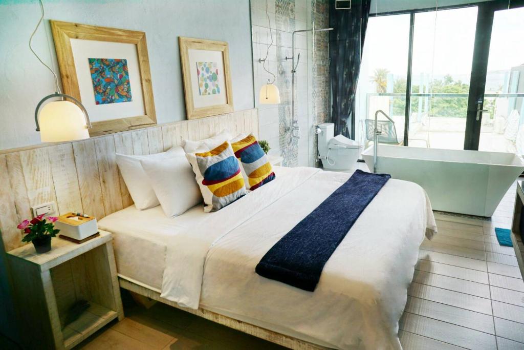 a bedroom with a large bed and a bath tub at 湛藍海岸民宿 Azure--這個夏天有點藍--墾丁南灣沙灘-可包棟-國旅卡特約店 in Nanwan