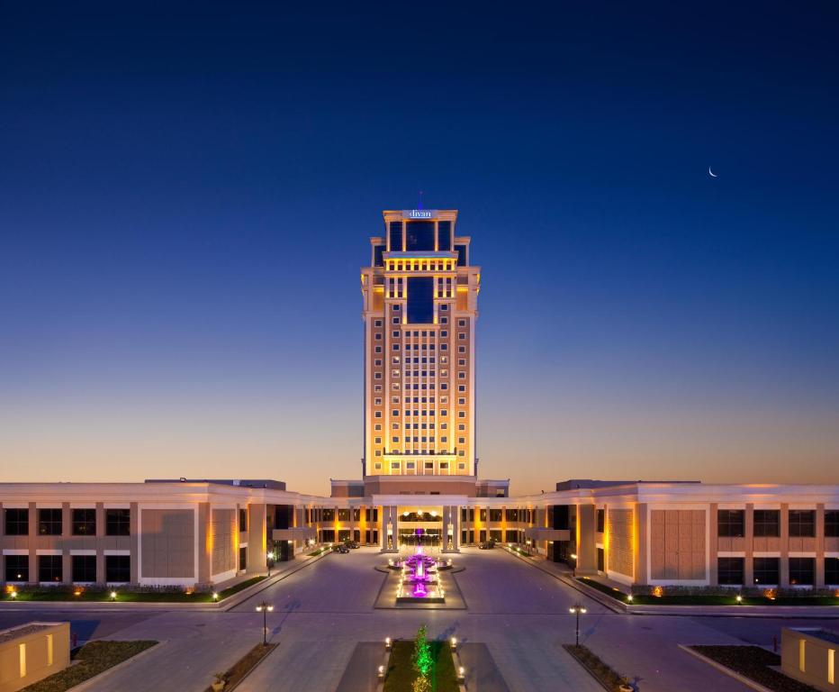 a large building with a lit up tower at night at Divan Erbil Hotel in Erbil