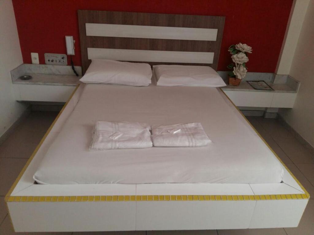 uma grande cama branca com duas almofadas em Motel Delamar (Adult Only) em Belo Horizonte
