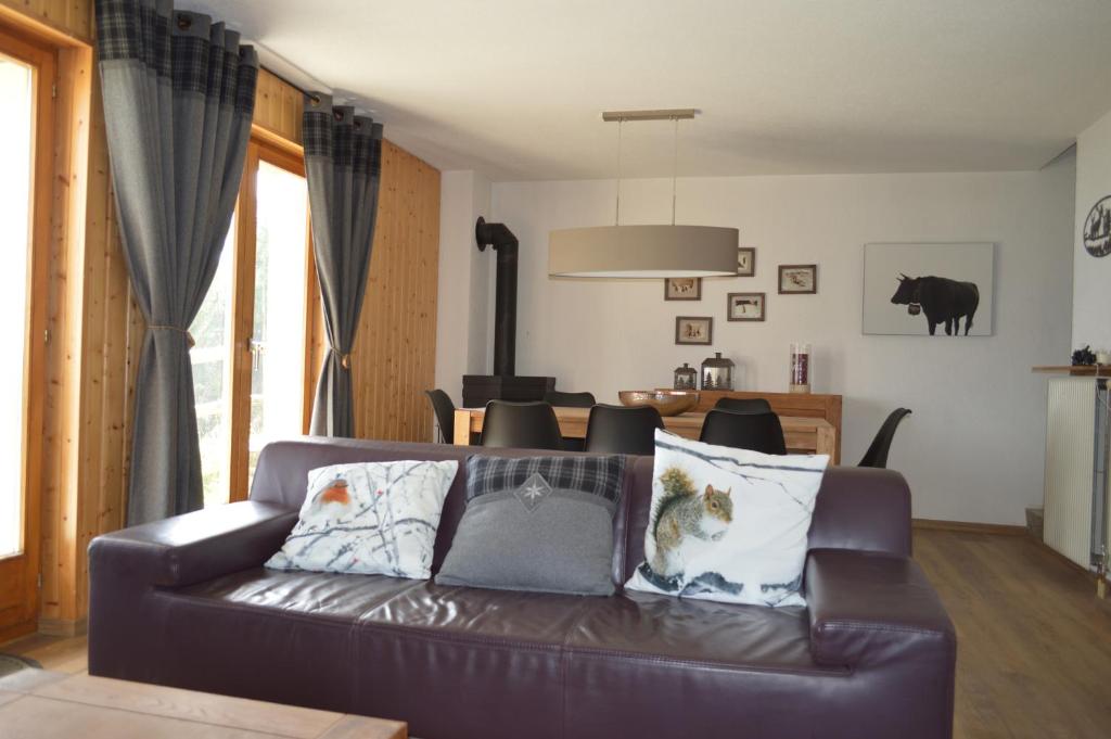 a living room with a brown leather couch with pillows at "Chalet le Dahlia - 4 Vallees" in Les Collons