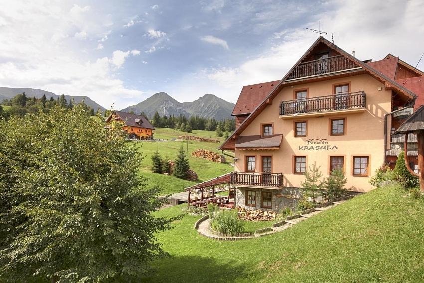 a large house on a hill with mountains in the background at Penzion Krasula in Ždiar