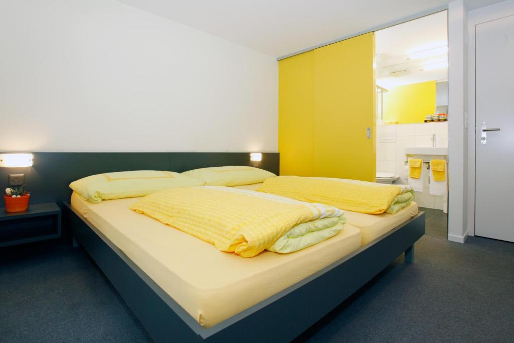 a bedroom with a large bed with yellow sheets at Hotel Krone in Attinghausen