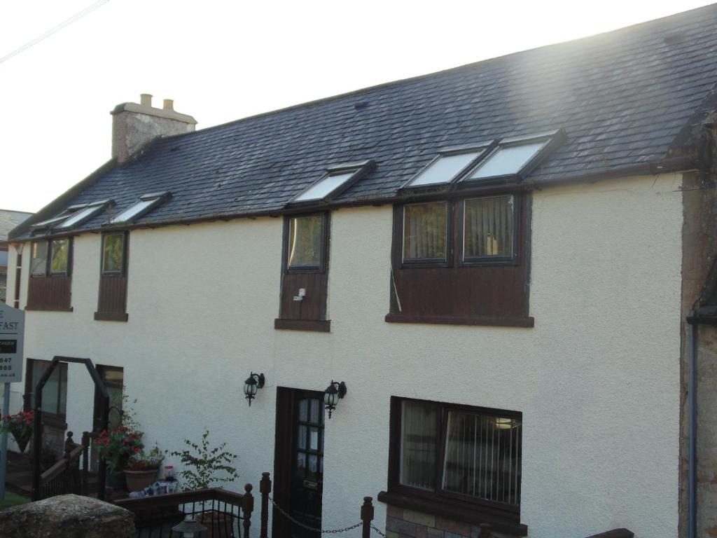 une maison blanche avec des fenêtres et un toit noir dans l'établissement Westmore Bed & Breakfast, à Alness