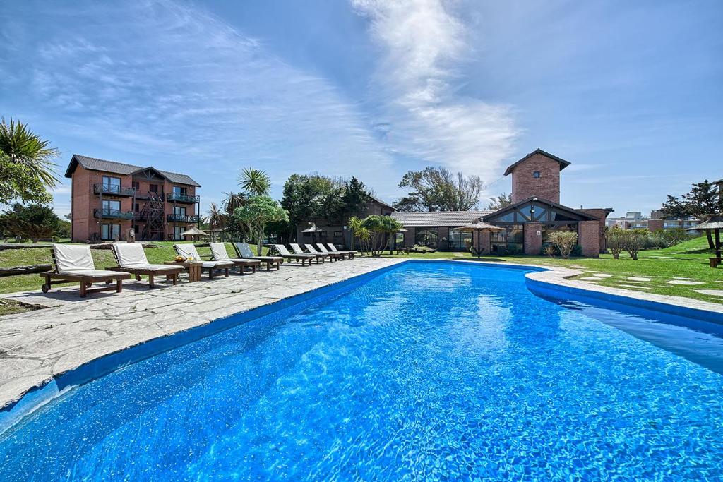 a swimming pool with chairs and a house at Marina Green Club in Villa Gesell