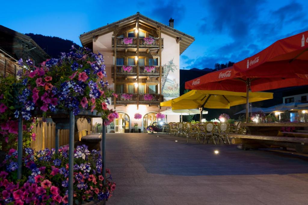 budynek z kwiatami, stołami i parasolami w obiekcie B&B Via Vai w Livigno