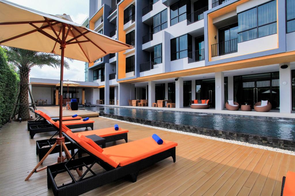 a pool with chairs and umbrellas next to a building at The Zense Boutique Hotel in Phitsanulok