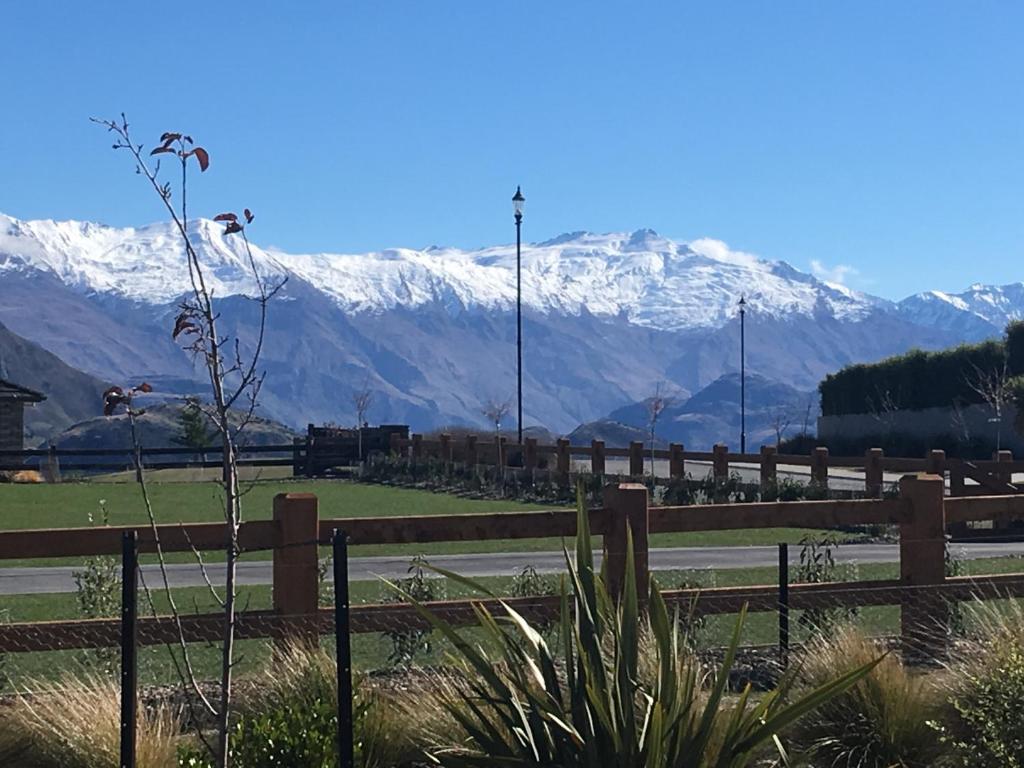 a fence with a snow covered mountain in the background at Minaret Ridge Retreat in Wanaka