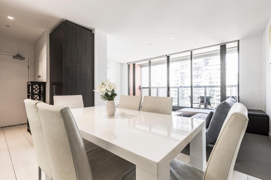a white dining room with a white table and chairs at UWS Madison Melbourne CBD Apartment in Melbourne
