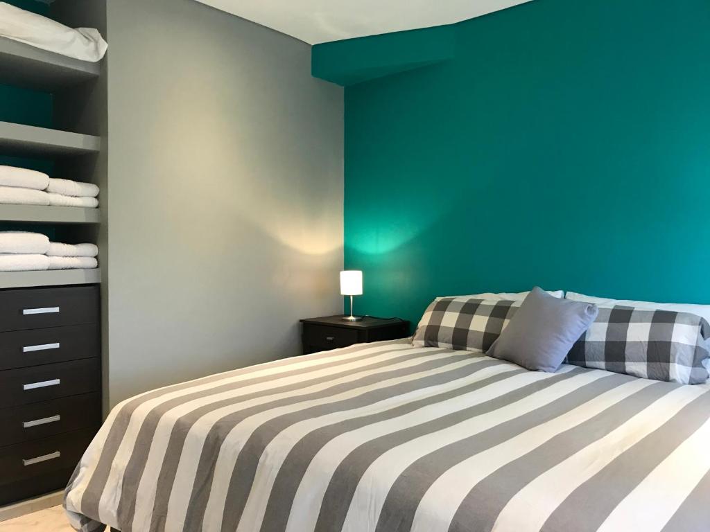1 dormitorio con 1 cama con pared azul en LaTorre Aparts en El Calafate