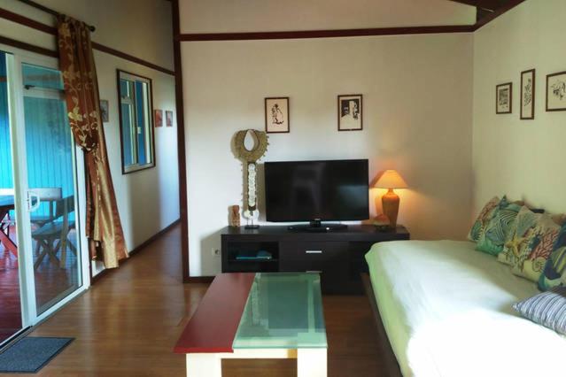 sala de estar con sofá y TV de pantalla plana en Otemanu Ninamu Fare en Bora Bora