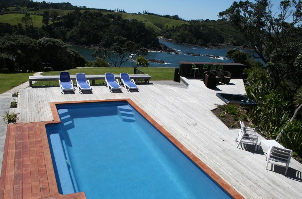 a swimming pool with chairs and a view of the water at The Lighthouse Lookout in Tutukaka