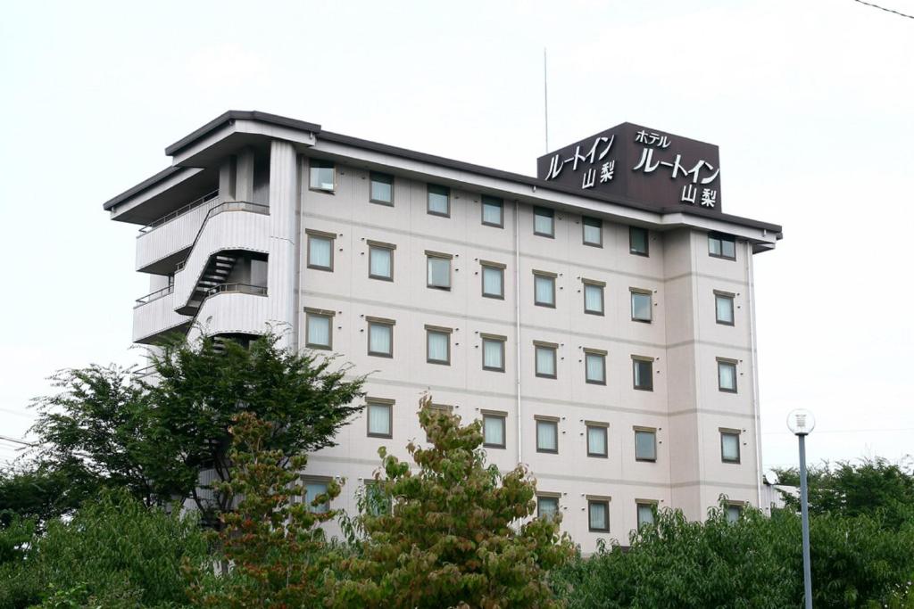 ein weißes Gebäude mit einem Schild darüber in der Unterkunft Hotel Route-Inn Court Yamanashi in Yamanashi