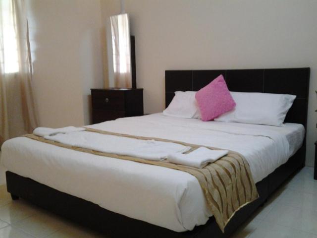 een groot bed met een roze kussen erop bij Alisa Homestay in Sungkai