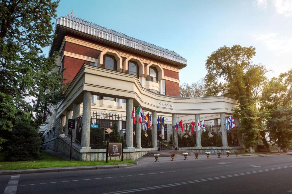 een gebouw met Amerikaanse vlaggen ervoor bij The Dostyk Hotel in Alma-Ata