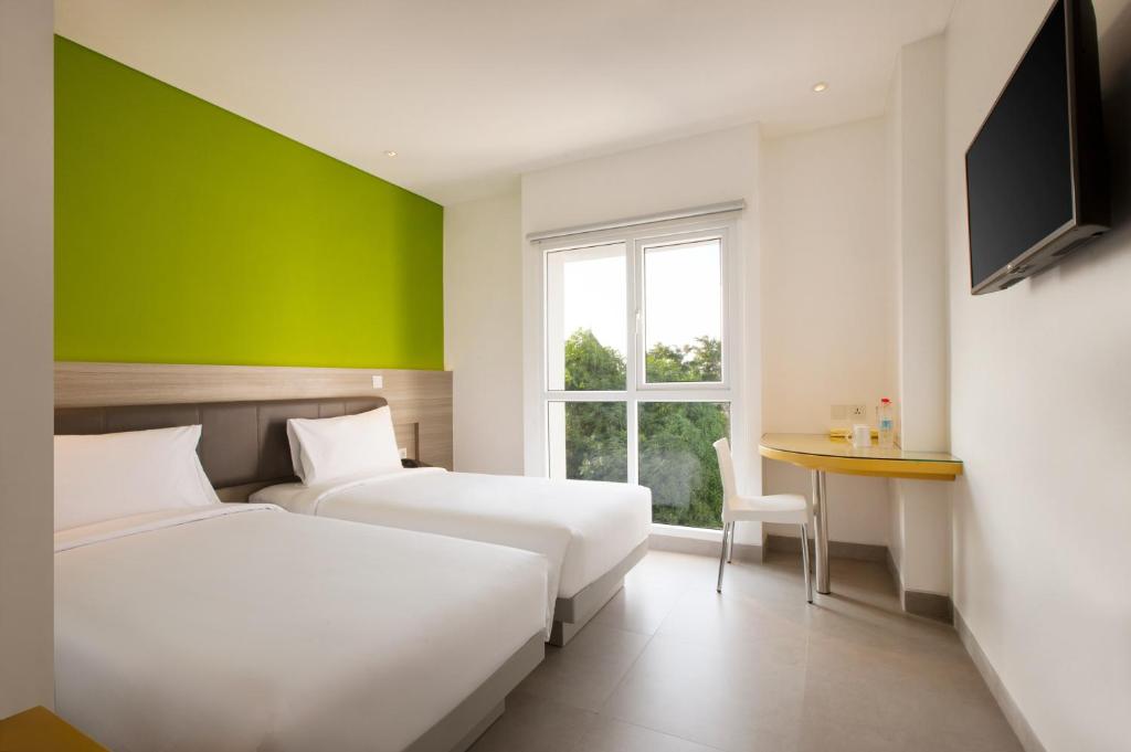 2 łóżka w pokoju z zieloną ścianą w obiekcie Amaris Hotel Darmo Surabaya w mieście Surabaja