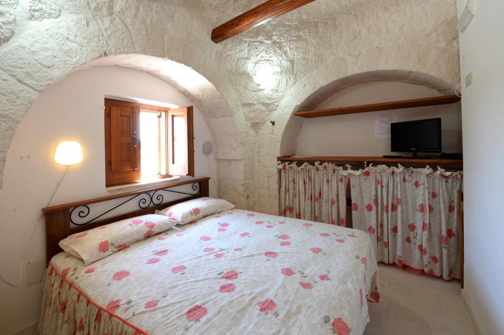 ein Schlafzimmer mit einem Bett in einem Zimmer mit einem Fenster in der Unterkunft Agriturismo con Trullo in Alberobello