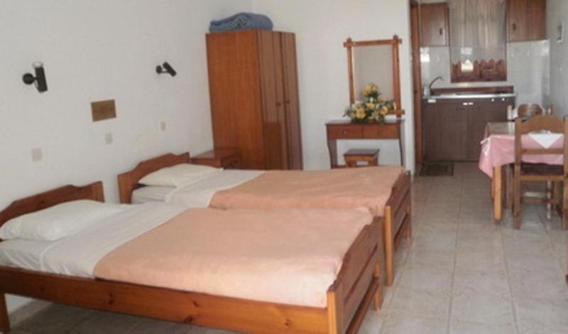 a bedroom with two beds and a table and a kitchen at Princess Studios in Afiartis