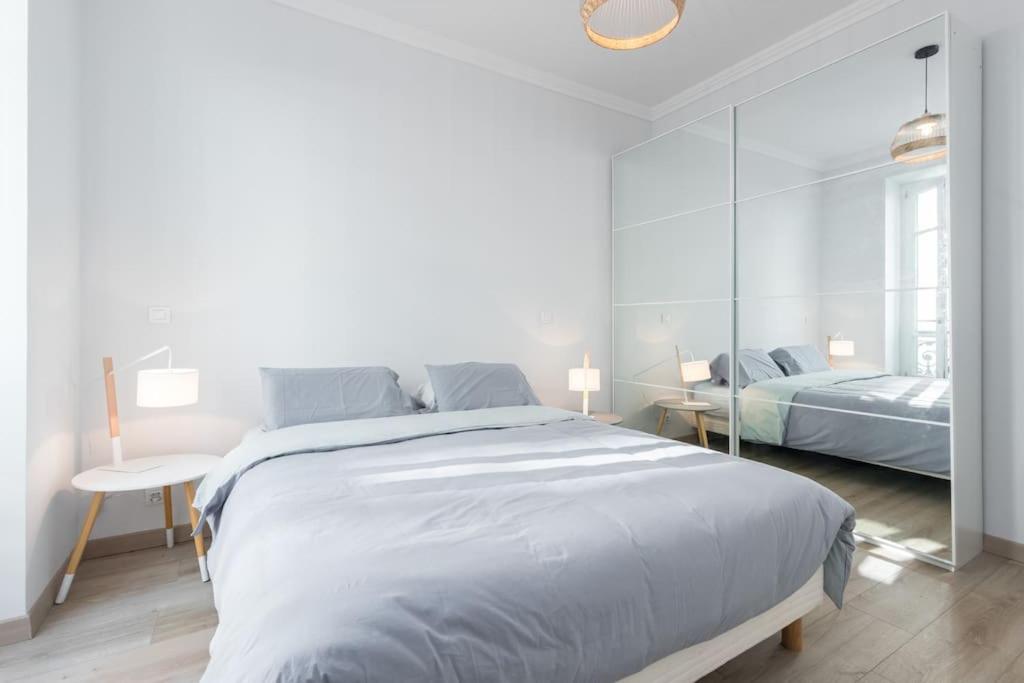 a white bedroom with a large bed and a mirror at Holiday apartment - Nice in Nice