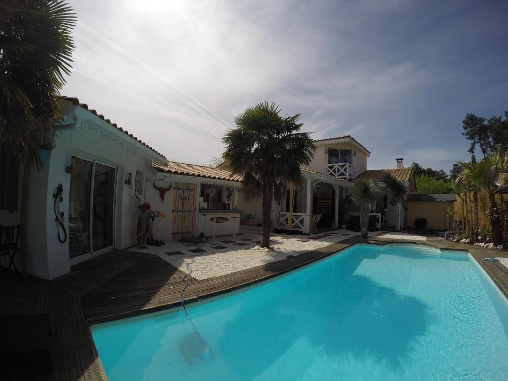 a large blue swimming pool in front of a house at Villa Caraîbes in Gujan-Mestras