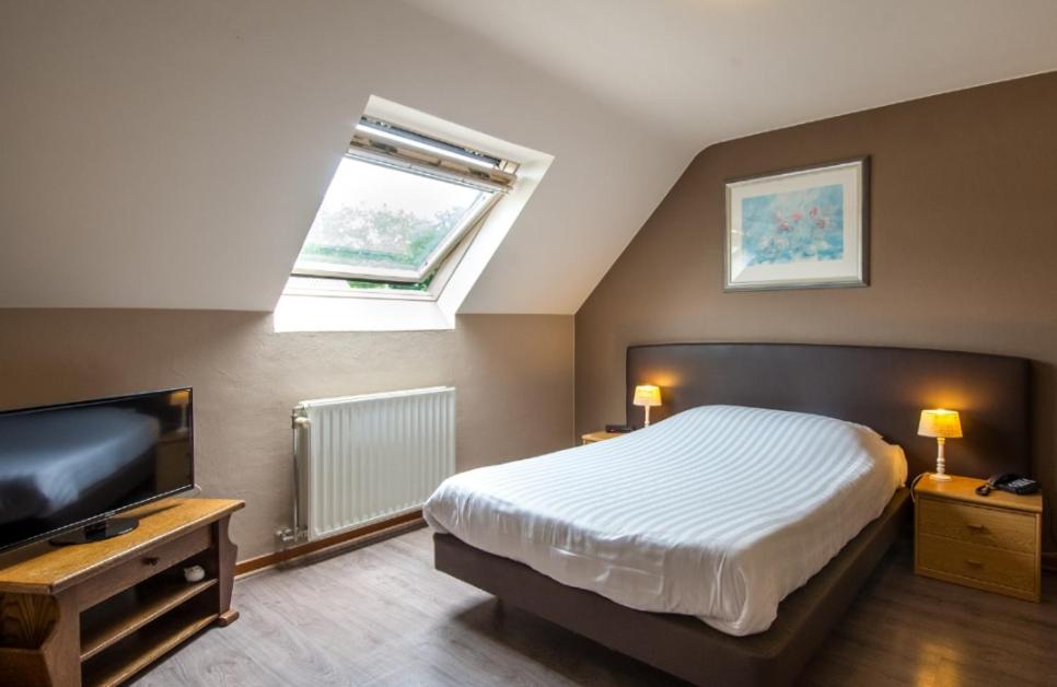 a bedroom with a bed and a flat screen tv at Hotel Lommel Broek in Kerkhoven