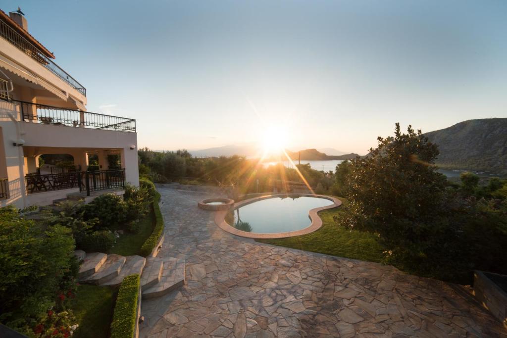 a view of a house with a swimming pool and the sunset at Our Dreamhouses in Loutraki Heraion Sea Lake in Loutraki