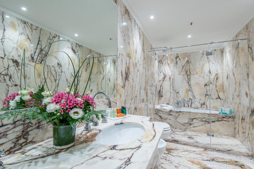 a bathroom with a sink and flowers on the wall at Hotel Nani Mocenigo Palace in Venice