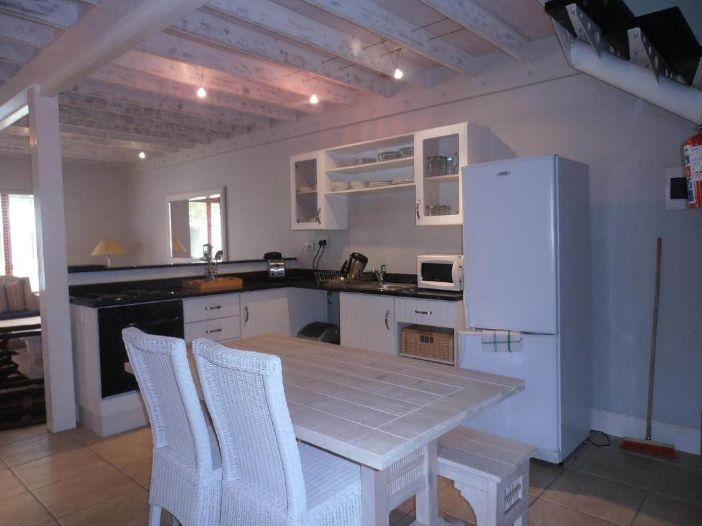 Una cocina con una mesa y un refrigerador blanco. en 75 The Dunes, en Plettenberg Bay