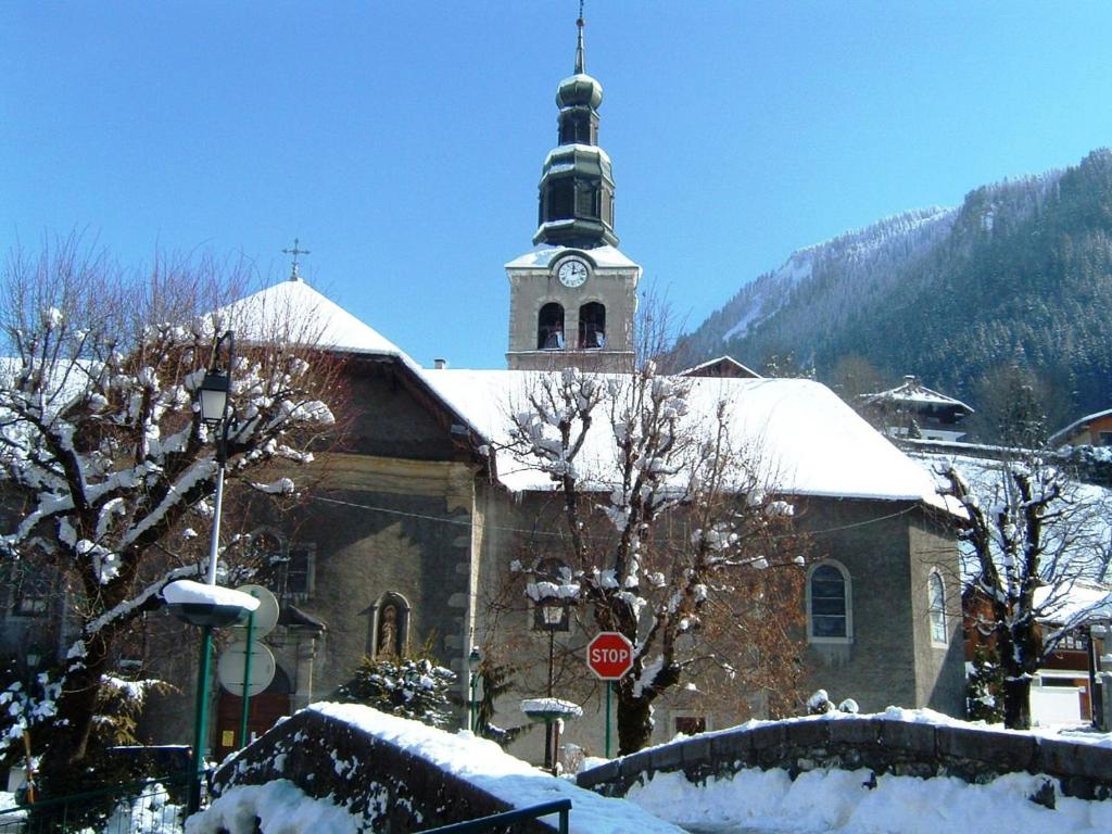 a church with a clock tower with snow on it at Chalet Leslie in Morzine