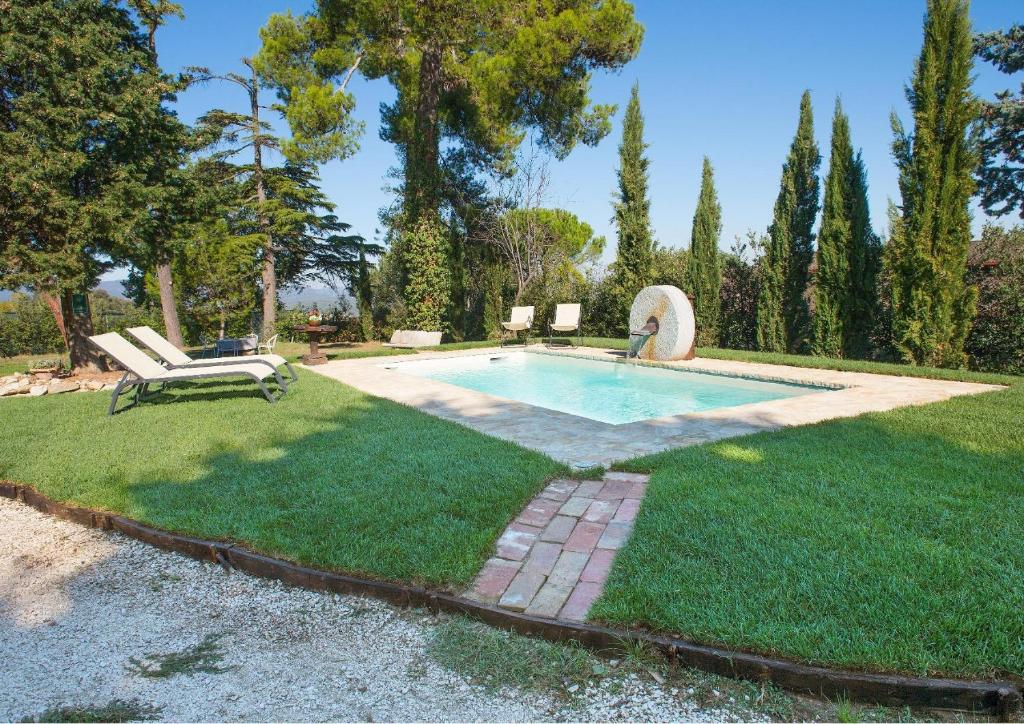 a swimming pool in a yard with a bench in the grass at Il Granaio in San Venanzo