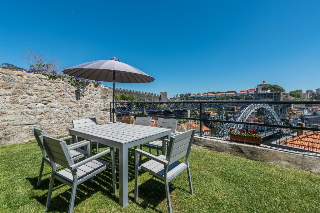 a table and chairs with an umbrella on the grass at Casa Dona Olga River View in Porto